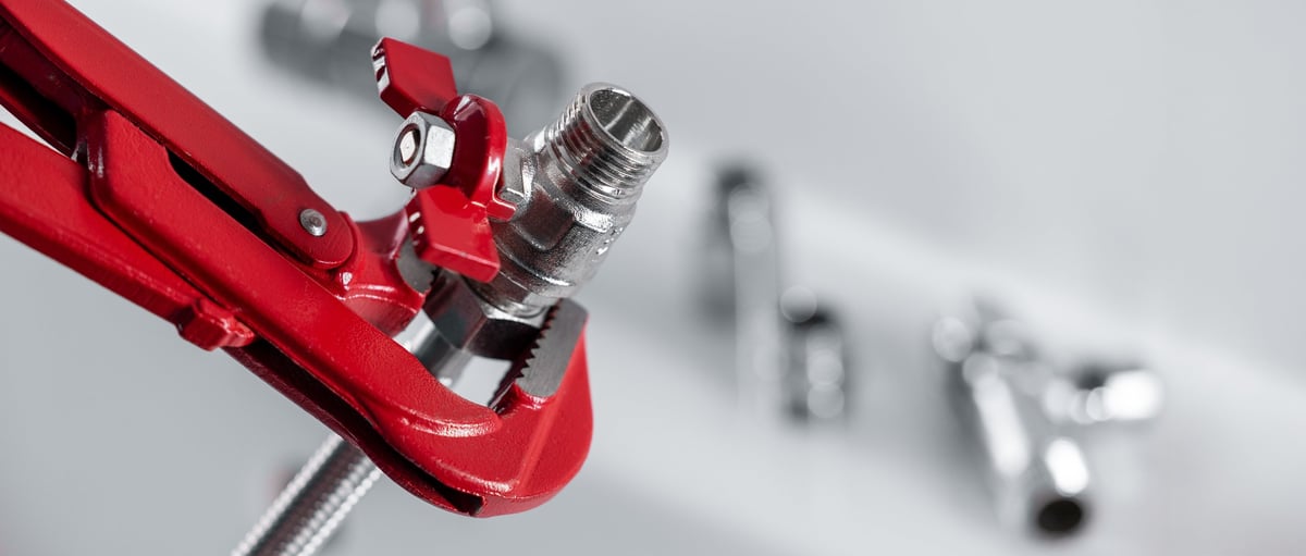 Close-up of a tap and water valve with plumbing tools